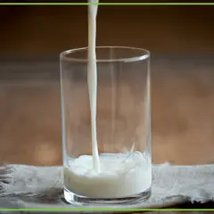 Mleko lejące się do szklanki na lnianej serwetce.