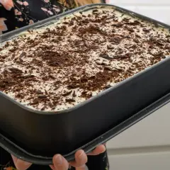 Gotowe do schłodzenia tanie ciasto bez pieczenia z herbatnikami, posypane wiórkami czekolady.