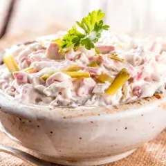 Niemiecka sałatka ziemniaczana z ogórkiem i jajkiem, kremowa i pyszna, ozdobiona natką pietruszki.