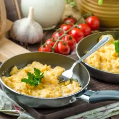Pyszna jajecznica z 2 jajek, podana na patelni z natką pietruszki. Zastanawiasz się, ile kcal ma jajecznica z 2 jajek? To idealny początek dnia!