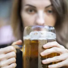 Kobieta pije piwo z dużego kufla. Czy zastanawiasz się nad piwo kcal?