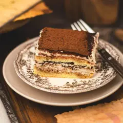 Pyszny kawałek najprostszego tiramisu, posypany kakao, na ozdobnym talerzyku. Idealny deser na każdą okazję.