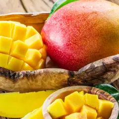 Soczyste mango, pokrojone w kostkę i w całości, w drewnianych miseczkach. Idealne na zdrową przekąskę, z niskim mango kcal.