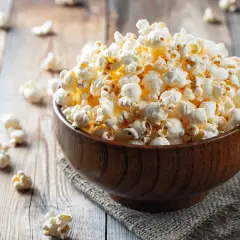 Pyszna miska popcornu na drewnianym stole. Zastanawiasz się nad popcorn kcal?