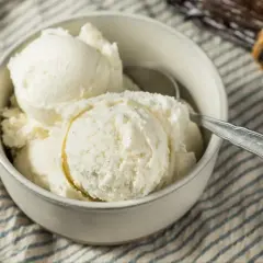 Puszyste lody z mascarpone w miseczce, gotowe do schrupania. Obok leżą laski wanilii.