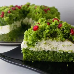Zielony tort z kremem, ozdobiony jak runo leśne z nasionkami granatu.
