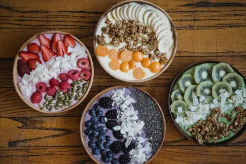 Cztery kolorowe smoothie bowls z owocami, granolą i nasionami. Idealne na śniadanie, gdy chcesz wiedzieć, jakie płatki owsiane kcal wybrać.