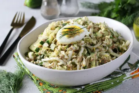 Lekka sałatka z tuńczykiem, jajkiem i ogórkiem, udekorowana koperkiem. Idealna na szybki lunch.