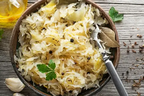 Miseczka pełna aromatycznej surówki z kiszonej kapusty, doprawionej pieprzem i kminkiem, z widelcem gotowym do degustacji.