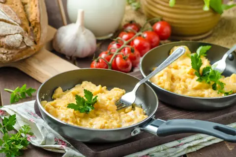 Pyszna jajecznica z 2 jajek, podana na patelni z natką pietruszki. Zastanawiasz się, ile kcal ma jajecznica z 2 jajek? To idealny początek dnia!