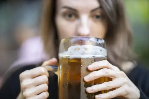 Kobieta pije piwo z dużego kufla. Czy zastanawiasz się nad piwo kcal?