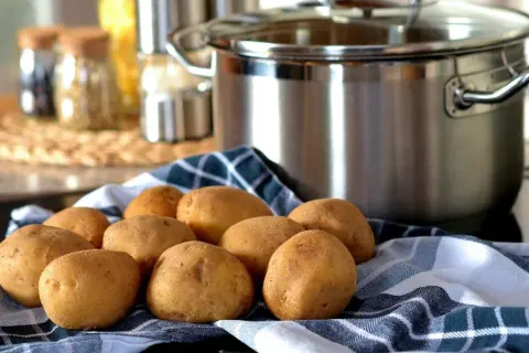 Ziemniaki na ręczniku, garnek w tle. Czas zacząć gotowanie, ale kiedy solić ziemniaki?