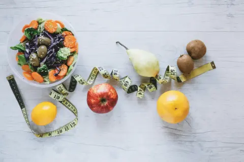 Sałatka, owoce i miarka krawiecka symbolizują zdrowy styl życia i dietę FODMAP.