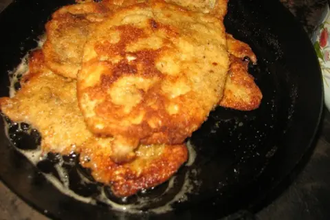 Złociste kotlety smażą się na patelni. Wyglądają na chrupiące, idealne, gdy stosuje się panierkę bez jajka.