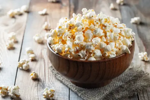 Pyszna miska popcornu na drewnianym stole. Zastanawiasz się nad popcorn kcal?