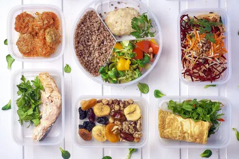 Pyszny, bezglutenowy jadłospis w pojemnikach: łosoś, kotleciki, kasza, sałatka, omlet, owoce i orzechy.