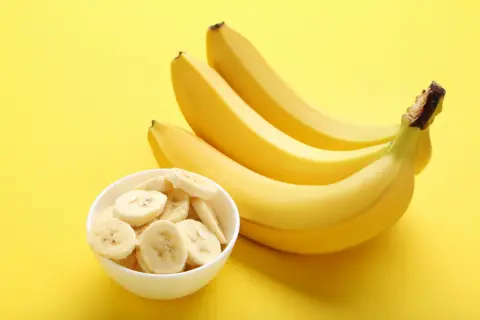 Kilka dojrzałych bananów i miseczka pokrojonych plasterków. Banan kalorie są niskie, co czyni go świetną przekąską.