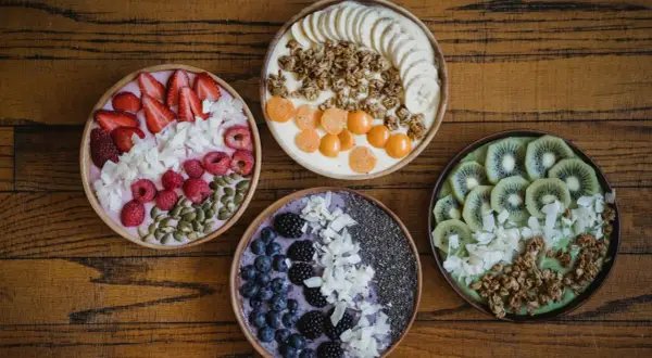 Cztery kolorowe smoothie bowls z owocami, granolą i nasionami. Idealne na śniadanie, gdy chcesz wiedzieć, jakie płatki owsiane kcal wybrać.