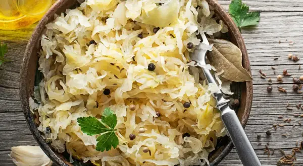 Miseczka pełna aromatycznej surówki z kiszonej kapusty, doprawionej pieprzem i kminkiem, z widelcem gotowym do degustacji.
