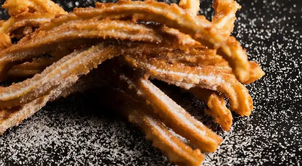 Churros co to? Złociste, chrupiące paluszki z ciasta smażonego na głębokim tłuszczu, posypane cukrem. Idealna przekąska.