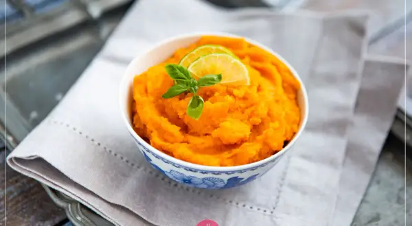 Puszyste, pomarańczowe bataty gotowane, udekorowane plasterkami limonki i listkiem bazylii. Idealne jako dodatek do obiadu.