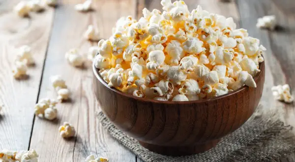 Pyszna miska popcornu na drewnianym stole. Zastanawiasz się nad popcorn kcal?