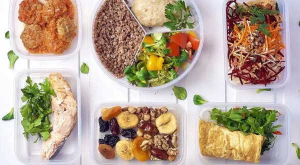Pyszny, bezglutenowy jadłospis w pojemnikach: łosoś, kotleciki, kasza, sałatka, omlet, owoce i orzechy.