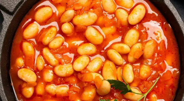 Pyszna fasolka po bretońsku przepis w garnku. Aromatyczne danie z białej fasoli w sosie pomidorowym, ozdobione natką pietruszki.