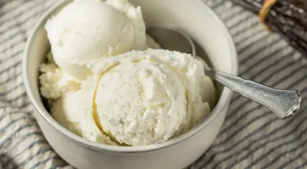 Puszyste lody z mascarpone w miseczce, gotowe do schrupania. Obok leżą laski wanilii.