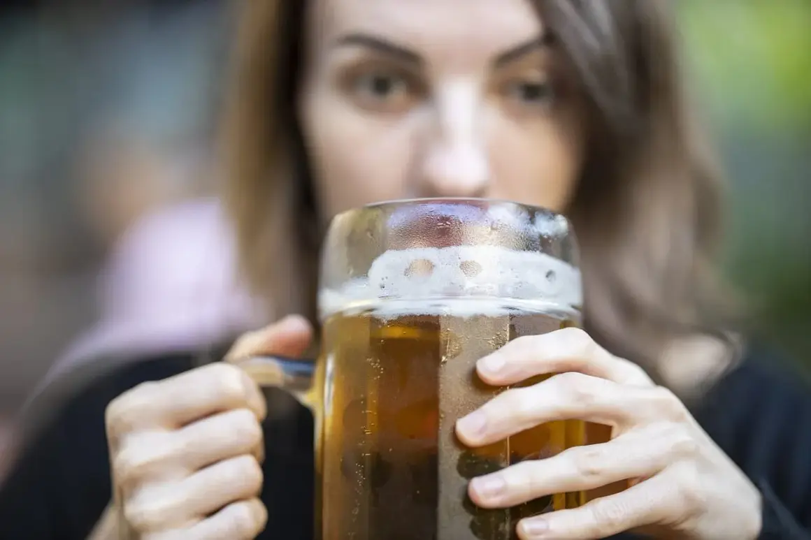 Kobieta pije piwo z dużego kufla. Czy zastanawiasz się nad piwo kcal?