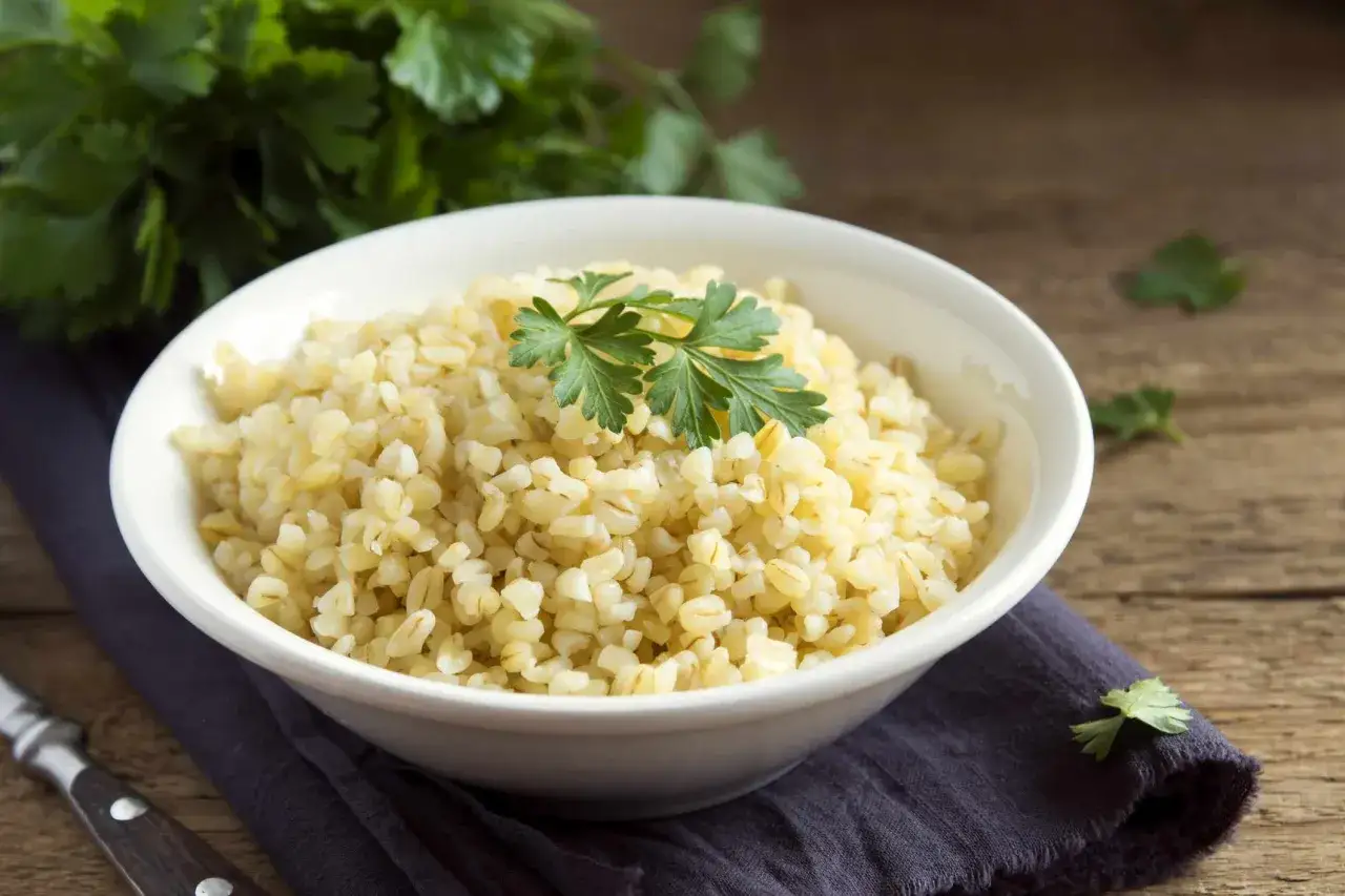 Miseczka kaszy bulgur, która ma niski indeks glikemiczny, udekorowana natką pietruszki.