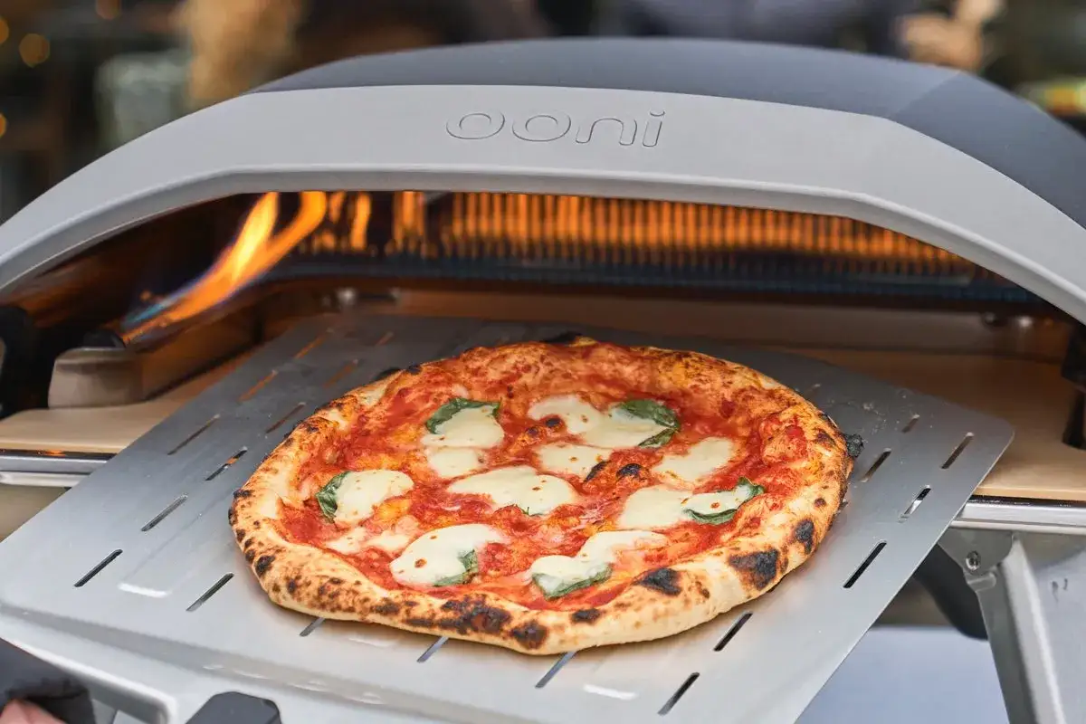 Piec Ooni w akcji! Pyszna, gorąca pizza margherita właśnie wyszła z pieca, gotowa do podania.
