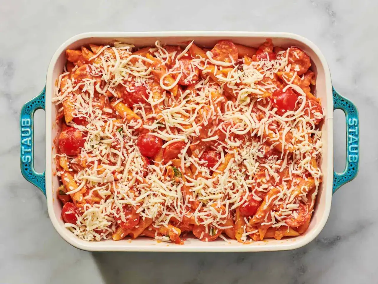 Penne z sosem pomidorowym i mnóstwem tartej mozzarelli w naczyniu Staub.