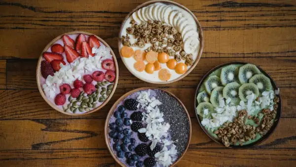 Cztery kolorowe smoothie bowls z owocami, granolą i nasionami. Idealne na śniadanie, gdy chcesz wiedzieć, jakie płatki owsiane kcal wybrać.
