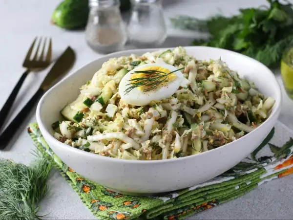 Lekka sałatka z tuńczykiem, jajkiem i ogórkiem, udekorowana koperkiem. Idealna na szybki lunch.