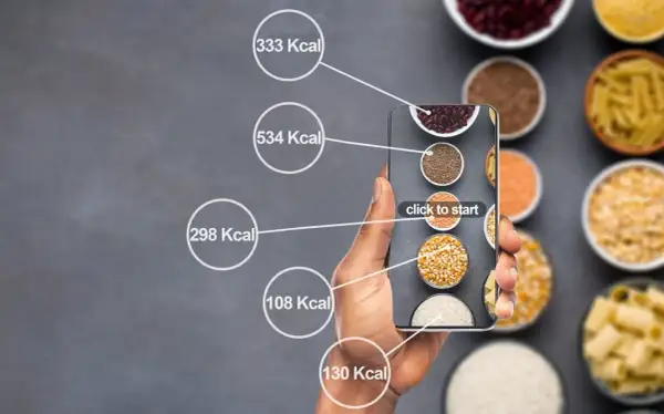Dłoń trzyma smartfon z aplikacją do liczenia kalorii. Na ekranie widać różne produkty spożywcze i ich kaloryczność, pomocne przy diecie 1500 kcal.