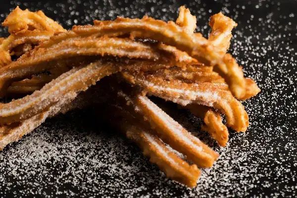 Churros co to? Złociste, chrupiące paluszki z ciasta smażonego na głębokim tłuszczu, posypane cukrem. Idealna przekąska.