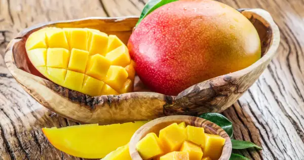 Soczyste mango, pokrojone w kostkę i w całości, w drewnianych miseczkach. Idealne na zdrową przekąskę, z niskim mango kcal.