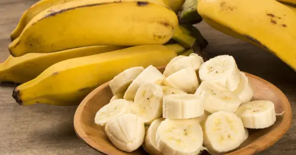 Kawałki banana na drewnianej misce, obok całe owoce. Idealna przekąska, gdy zastanawiasz się nad banan kcal.