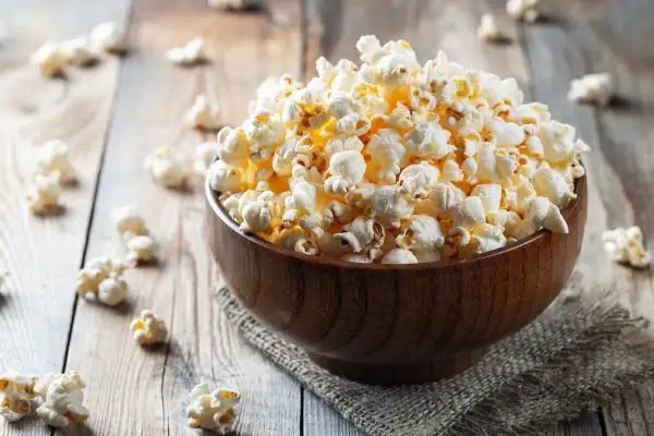 Pyszna miska popcornu na drewnianym stole. Zastanawiasz się nad popcorn kcal?