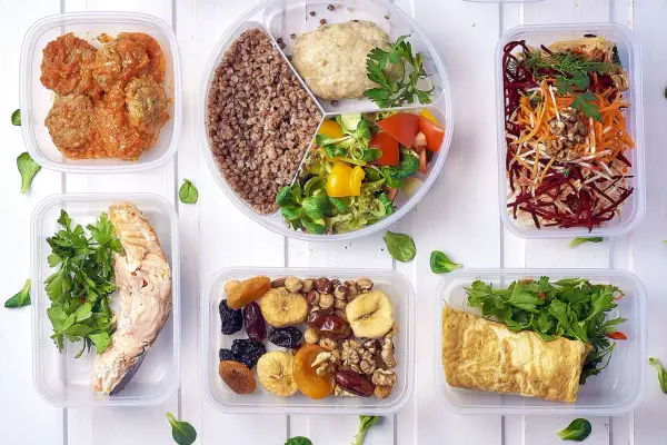 Pyszny, bezglutenowy jadłospis w pojemnikach: łosoś, kotleciki, kasza, sałatka, omlet, owoce i orzechy.