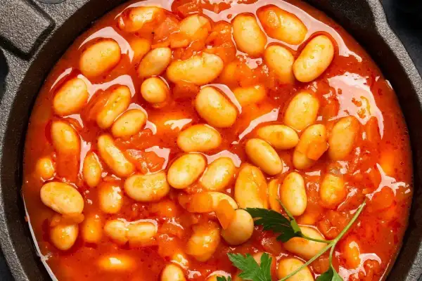 Pyszna fasolka po bretońsku przepis w garnku. Aromatyczne danie z białej fasoli w sosie pomidorowym, ozdobione natką pietruszki.